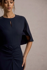 Dettaglio dell'abito blu navy con scollatura a goccia e pieghe raffinate sulla vita