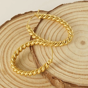 Vintage oval twisted hoop earrings in gold titanium steel on a rustic wooden base