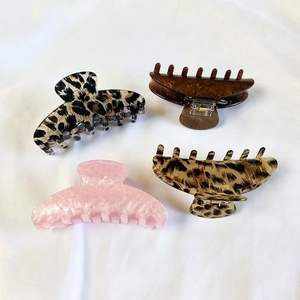Close-up of assorted leopard print and tortoiseshell plastic hair claw clips on white fabric