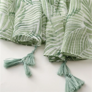 Close-up of green banana leaf print on airy scarf featuring delicate tassel fringe detail