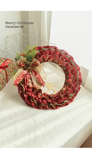 Detail of Christmas wreath with golden reindeer and pine cones on white faux fur carpet