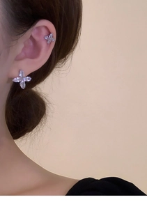 Detail of silver flower earrings with zircon inlays worn as studs and ear cuffs