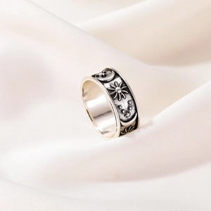 Retro silver ring featuring embossed sun moon and star patterns on cream silk background