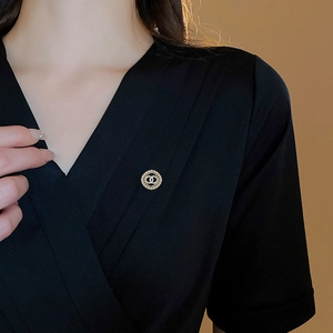 Close-up of a luxury gold brooch with clear rhinestones on a black garment