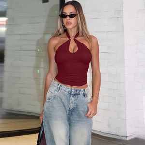Detail of burgundy halter top's criss-cross back design paired with denim jeans