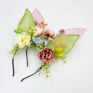 Dettaglio di due cerchietti a orecchie di coniglio con fiori di seta e foglie verdi