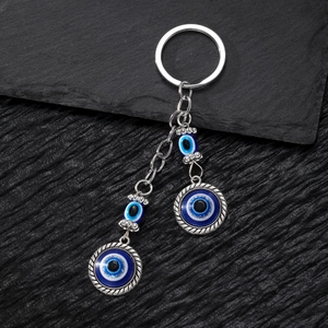 Macro detail of vintage tribal Hamsa hand keychain with blue evil eye on black stone