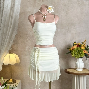 Detail of cream ruched two-piece set featuring 3D rose accent and ruffled hemline