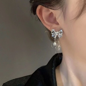 Close-up of bow earrings with pearls and a water drop pendant on model's ear