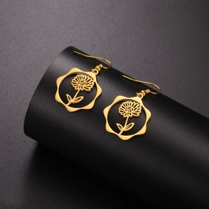 Detailed close-up of golden hollow flower earrings on a black display stand