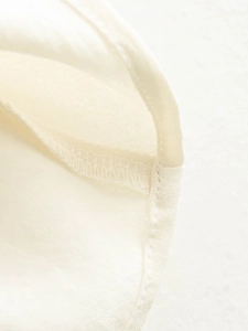 Detailed macro view of woven cream fabric texture and high-quality edge stitching