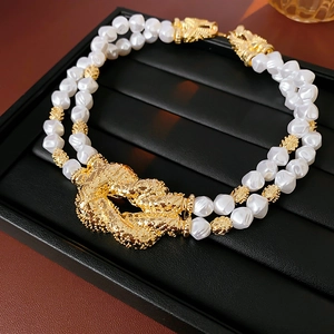 Close-up of double-strand pearl bracelet with a textured gold-tone knot on a display tray