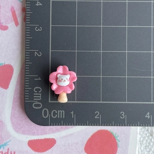 Detailed view of pink flower resin cat charm on a black grid mat with scale measurements