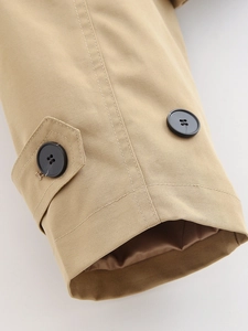 Detail of khaki cropped trench coat cuff featuring high-density twill fabric and black button