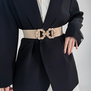 Detail of interlocking gold chain-textured buckle on a beige elastic corset waist belt