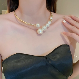 Detail of model wearing a gold choker with gradient white pearls and golden beads