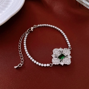Detail of silver flower necklace with emerald green stone on red silk background
