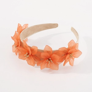 Détail de fleurs en résine orange avec perles dorées sur un bandeau en velours beige