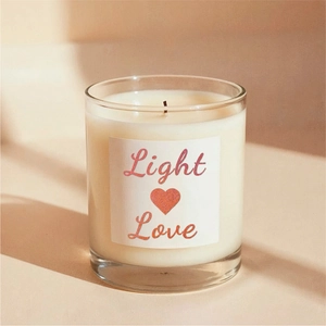 Detail of a white scented candle in a glass jar with a red glitter Light Love label