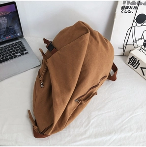 Detailed shot of brown canvas backpack on a white fabric with books and a laptop