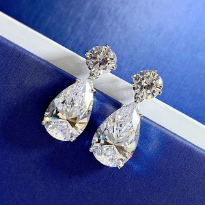 Macro shot of 925 silver pear-cut zircon earrings on a premium blue satin background