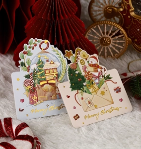 Close-up of gold-stamped Christmas greeting cards with snow globe and envelope designs