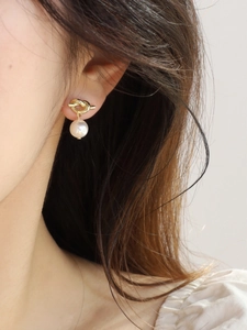Close-up of elegant gold knot pearl earrings worn by a model for a refined daily style