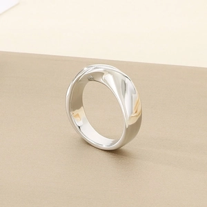 Close-up of polished stainless steel ring with a unique asymmetrical twisted design