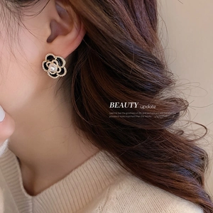French vintage black camellia earrings with gold edges and central pearl on model