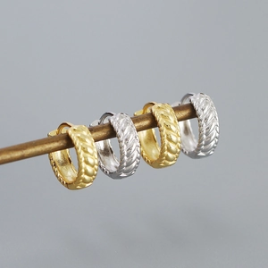 Macro shot of gold and silver S925 sterling silver hoop earrings with woven texture
