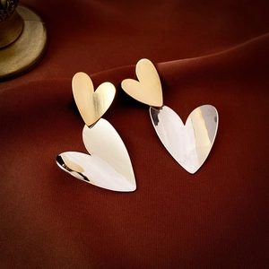 Detail of creative overlapping heart earrings with gold brushed and silver polished finish