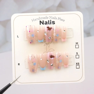 Detail of handmade press-on nails with star sequins and heart rhinestones on display card