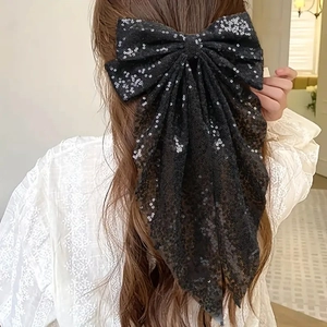 Détail d'un nœud papillon noir à paillettes avec rubans en tulle sur un mannequin