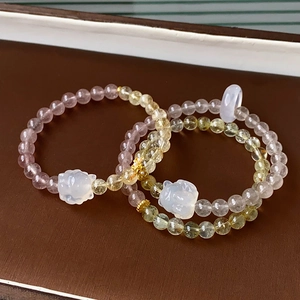 Detail of beaded gemstone bracelets with cat pendants on a brown leather tray
