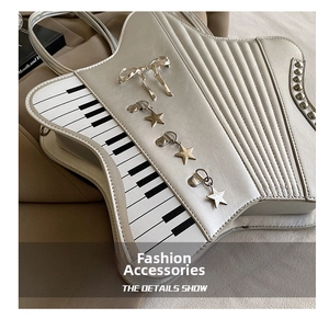 Detail view of piano key pattern and star charms on the cream musical instrument handbag