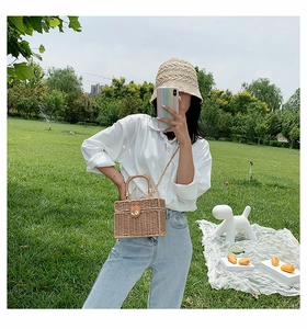 Outdoor-Lifestyle-Ansicht der geflochtenen Strohbox-Tasche mit goldenem Schloss und Griff
