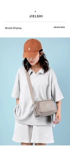 Compact light khaki nylon crossbody bag with multi-pocket design shown on model