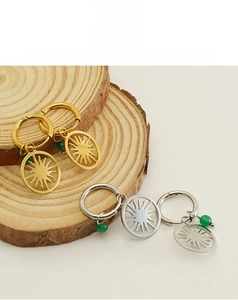 Detailed shot of gold and silver sun earrings with green beads on rustic wood slices