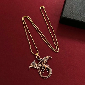 Vintage gold dragon wing pendant necklace on a deep red textured background with a bead chain