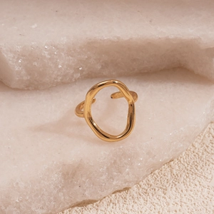 Detail of a minimalist gold irregular oval ring on a white raw crystal stone background