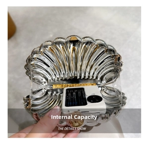 Close-up of shell-shaped silver evening bag showing inner capacity with a smartphone