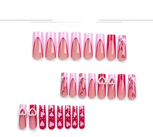 Detail of pink French press-on nails featuring 3D hearts, pearls, and strawberry patterns
