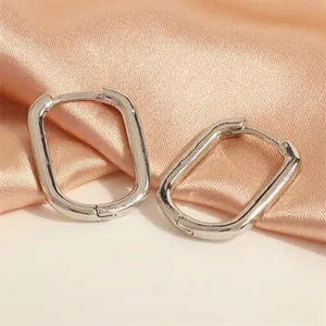 Detailed close-up of geometric silver U-shaped hoop earrings on elegant silk fabric