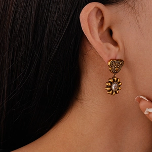 Macro detail of vintage bear and flower drop earring with zircon on model