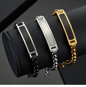 Detailed view of three stainless steel curb bracelets in gold, silver, and black finish