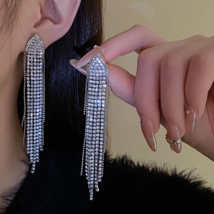 Detail of silver needle earrings featuring long geometric tassels with white rhinestones