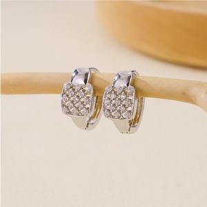 Elegant silver huggie hoop earrings with square pavé zircon on a natural wood stand