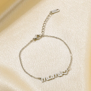 Detailed view of silver stainless steel mami bracelet with heart charm on gold silk cloth
