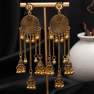 Vintage bohemian tassel earrings with carved floral details and small bells on a stand