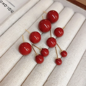 Detail of red globe stud earrings set in various sizes on white textured jewelry tray